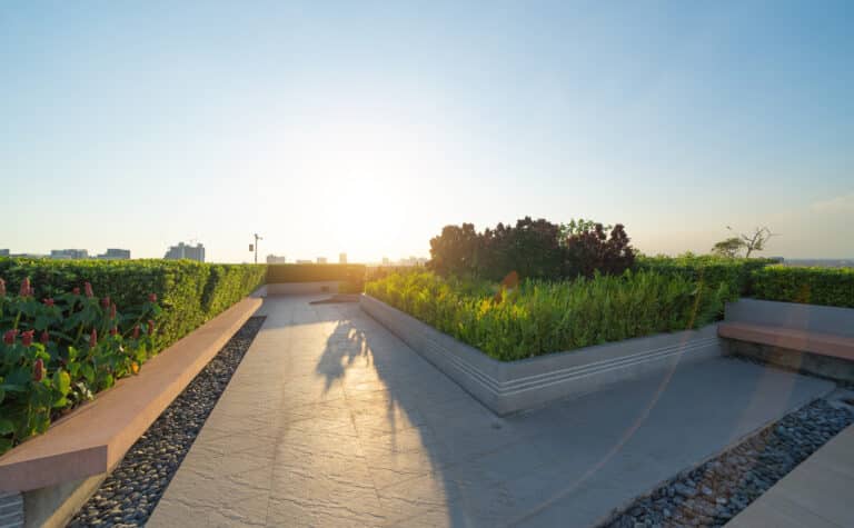 Sky garden on private rooftop of condominium or hotel, high rise architecture building with tree, grass field, and blue sky.